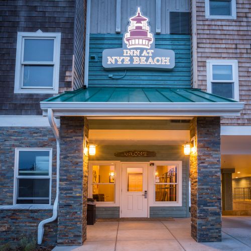 A hotel entrance with a sign reading &ldquo;New York New York&rdquo; above a covered doorway, brick and stone exterior, warm lights inside, and a small covered driveway area.