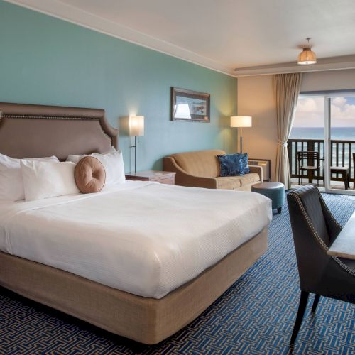 A cozy hotel room with a large bed, seating area, desk, and soft lighting. A soothing, modern retreat.